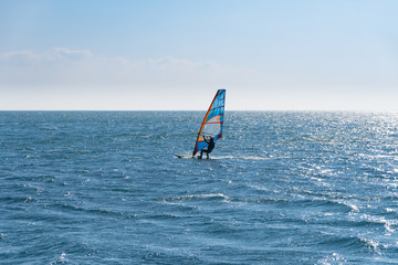 Windsurfing on the sea, backlit view.
