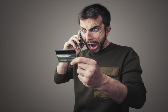 Angry young man having an argument with his bank for the credit card bill he received