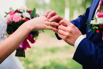 Obraz na płótnie Canvas groom puts a wedding ring on the bride's finger at the wedding ceremony