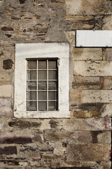Fototapeta na wymiar View of window and street sign on a stone wall in Cunda (Alibey)