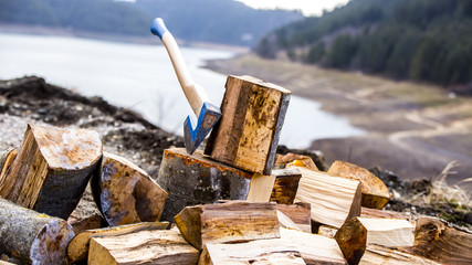 Axe stuck in a beech stub with wood blocks as background. On the mountain
