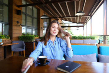Beautiful lady enjoying windy weather at cafe  . Pretty girl sitting on sofa with cup of tea,...