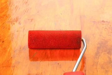 paint roll brush in white paint on plywood surface.