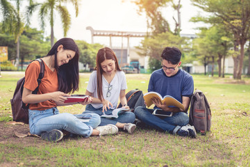 Group of Asian college student reading books and tutoring special class for exam on grass field at outdoors. Happiness and Education learning concept. Back to school concept. Teen and people theme.