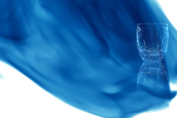 Empty shot of vodka or tequila with pattern enveloped in blue smoke.
