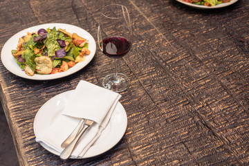tasty salad with wine on rustic wooden table