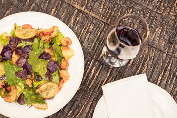 delicious salad with wine on rustic wooden table