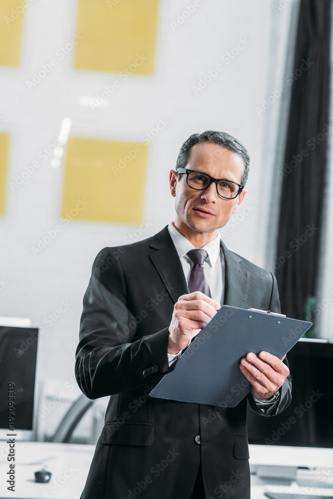 Wall mural portrait of focused businessman with notepad in office