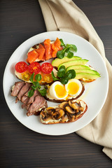 Bruschetta, assorted, different fillings, on plates with a soft-boiled egg in the middle