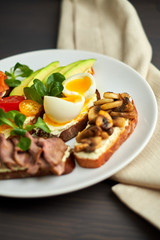 Bruschetta, assorted, different fillings, on plates with a soft-boiled egg in the middle