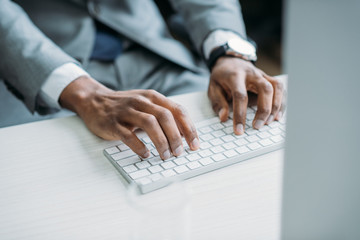 partial view of african american businessman typing on keyboard at workplace