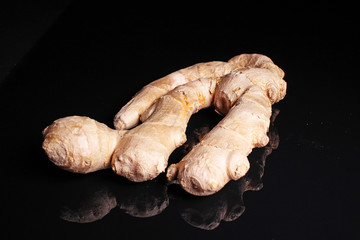 Ginger. Whole ginger on black reflective studio background. Isolated black shiny mirror mirrored background for every concept.