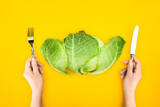 Top View Of Person Holding Fork And Knife While Eating Healthy Cabbage Isolated On Yellow