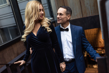 beautiful adult couple in stylish clothing going up stairs