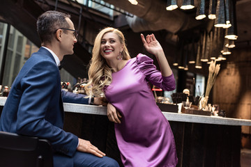 smiling woman flirting with handsome man at bar counter