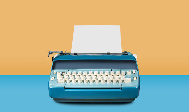 Old electric typewriter on blue table background