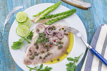 steamed skate wing with Caper olive oil on blue wooden background