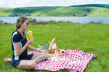 Young woman doing picnic on green lawn with beautiful view