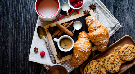 Top view of a wood table full of cakes, fruits, coffee, biscuits, spices and more