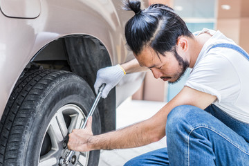 Obraz premium Fixing car engine in automobile repair garage. Handsome mechanics in uniform are repairing car while working in auto service