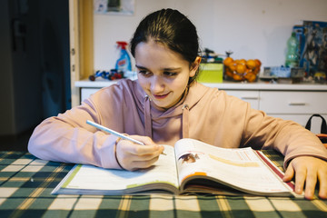 teenager performs homework in the home kitchen