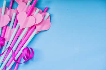 valentine's day holiday. bright pink and blue drinking straws with hearts and a pink ribbon on blue.bright sipping straws for party or birthday