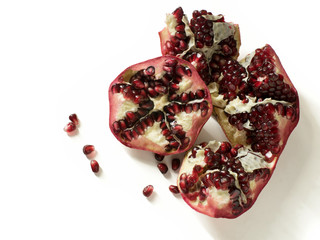 Close up of cut open pomegranate, with scattered pomegranate seeds, high angle - isolated on white background- 