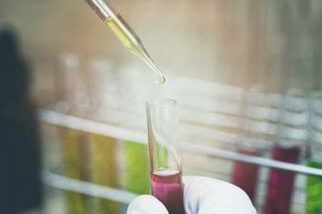 Researcher is dropping the reagent into test tube.Scientist working at the laboratory.
