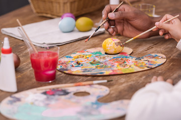 cropped image of african american father and daughter painting easter eggs