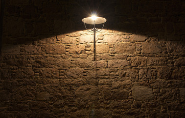 Night view of decorative street ligtht and stone wall.