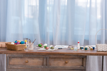 Painted easter eggs with paints and brushes on wooden table