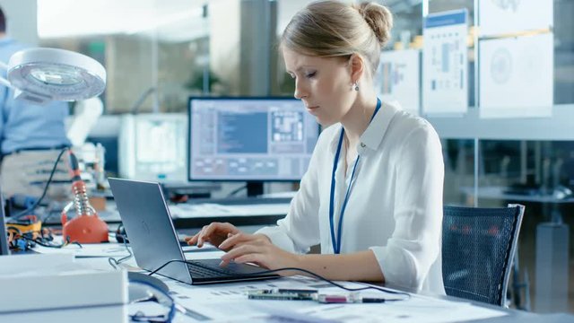 Female Computer Scientists Connects Circuit Board to Her Laptop and Starts Programming it. She Works in the Technologically Advanced Laboratory.