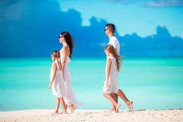 Young family walking on white tropical caribbean beach