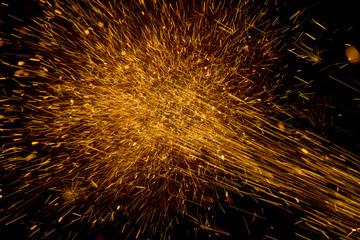 Glowing flow of sparks form cutting steel in the dark.