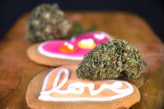 Dried cannabis nug with baked cookies on a wood tray