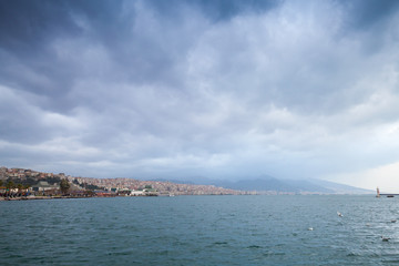 Fototapeta na wymiar Coastal cityscape under cloudy sky. Izmir
