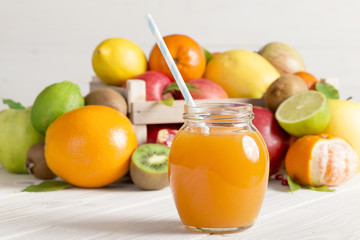 A glass of juice with a straw from different fruits