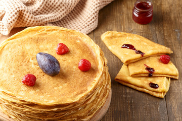 Thin hot pancakes with berries on the table
