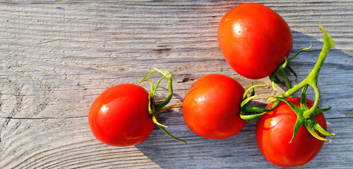 Red tomatoes on wooden surface. Wide photo.