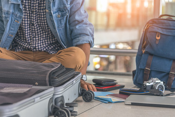 Young man traveler sitting on the floor at the airport terminal finding some stuff, or lost...