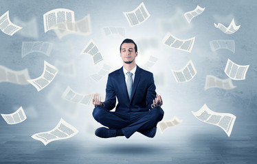 Businessman meditating with flying paper concept