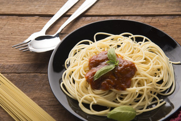 Spaghetti bolognese in black plate on wooden table background,Spaghetti with Spicy Mixed sauce and meat