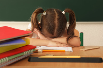 Sleeping little girl tired of doing homework in classroom