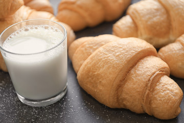 Tasty croissants and glass of milk on table