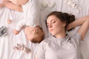 Mother with her baby sleeping on bed at home