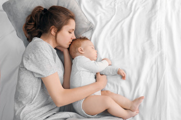Mother with her baby sleeping on bed at home