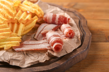 Potato chips with bacon on wooden board