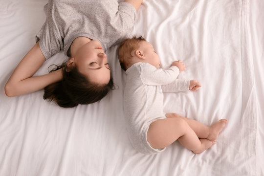 Mother with her baby sleeping on bed at home