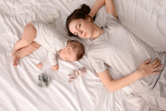 Mother with her baby sleeping on bed at home