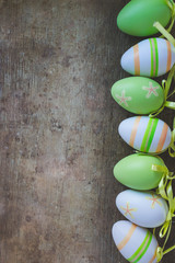 Top view of green, orange and white easter eggs decorations on old rustic, vintage wooden background, vintage toned. Easter eggs or decorations background